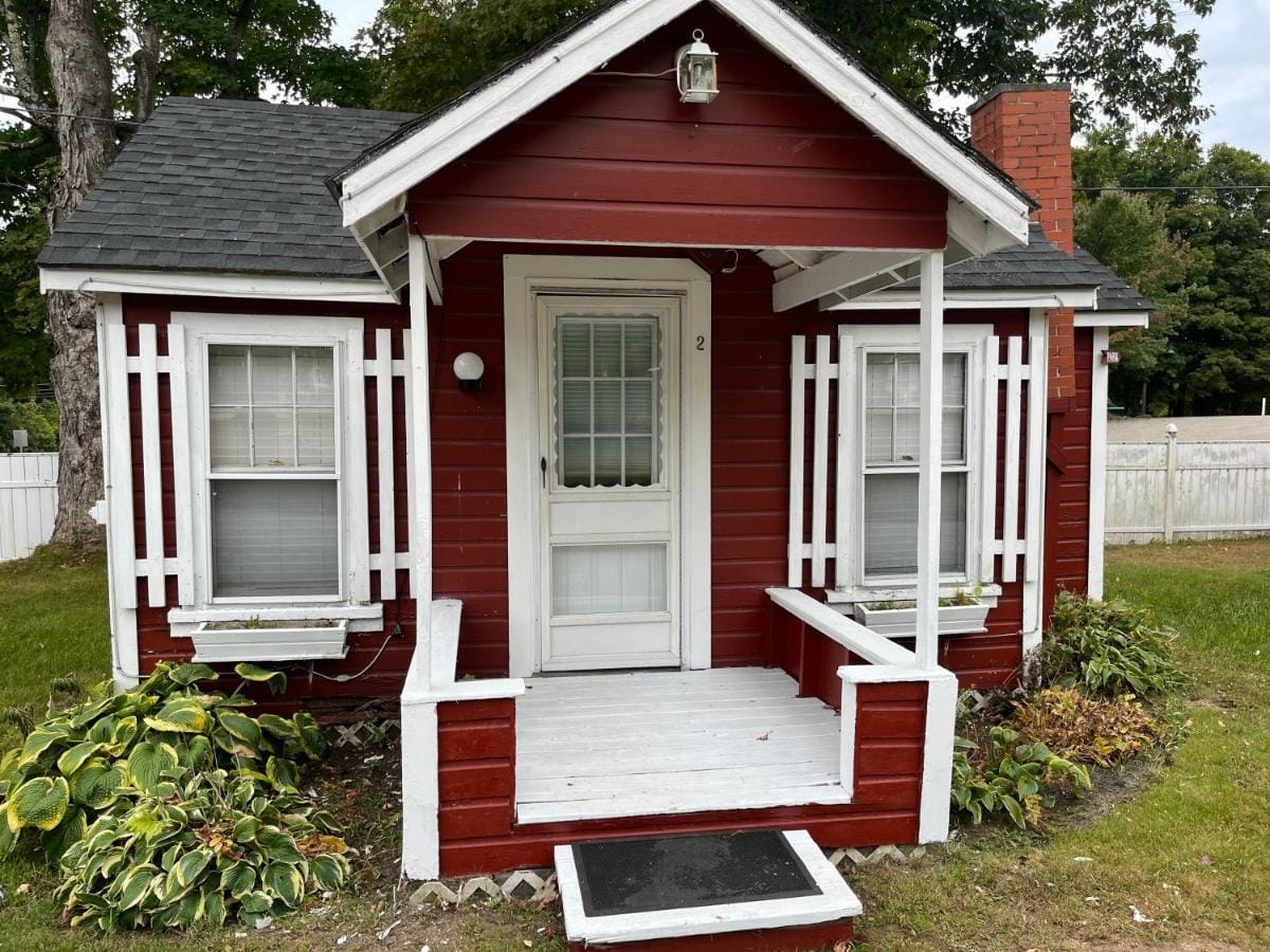 Cabin two in red clapboard with a white porch and hostas in bloom